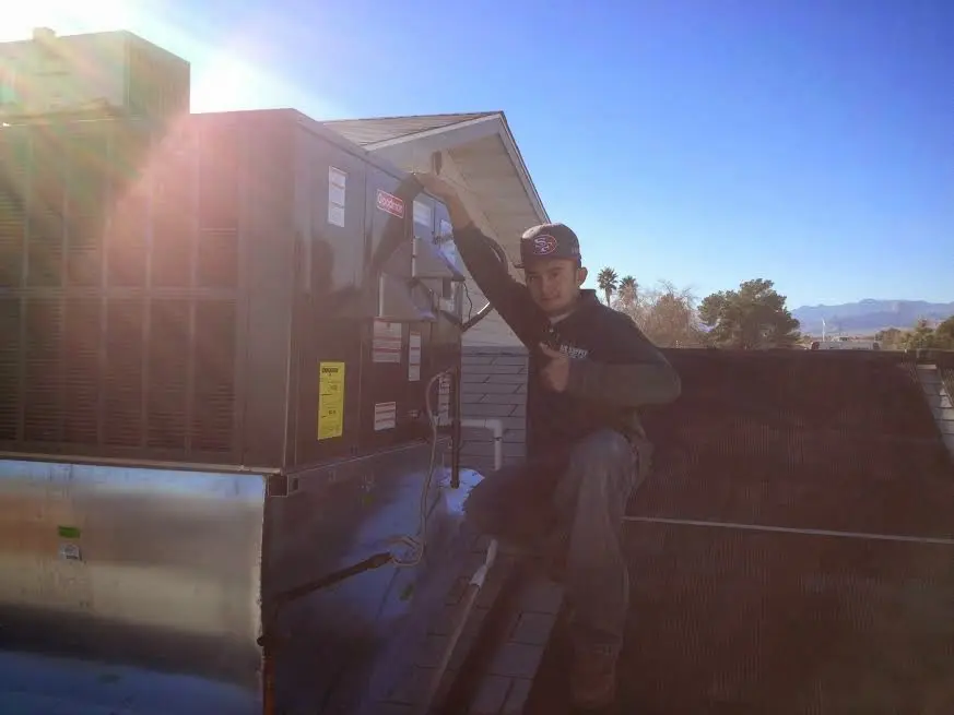HVAC technician performing Heat Pump Repair on a rooftop unit in Elsmere